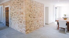 A modern interior with a stone accent wall, a wooden door, and a dining area with a table and chairs. - Ses Rotes by Rentallorca (Campanet)