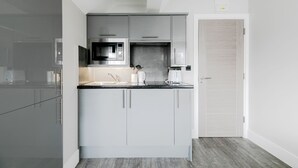 Una cocina moderna con armarios grises, un microondas integrado y una cafetera.