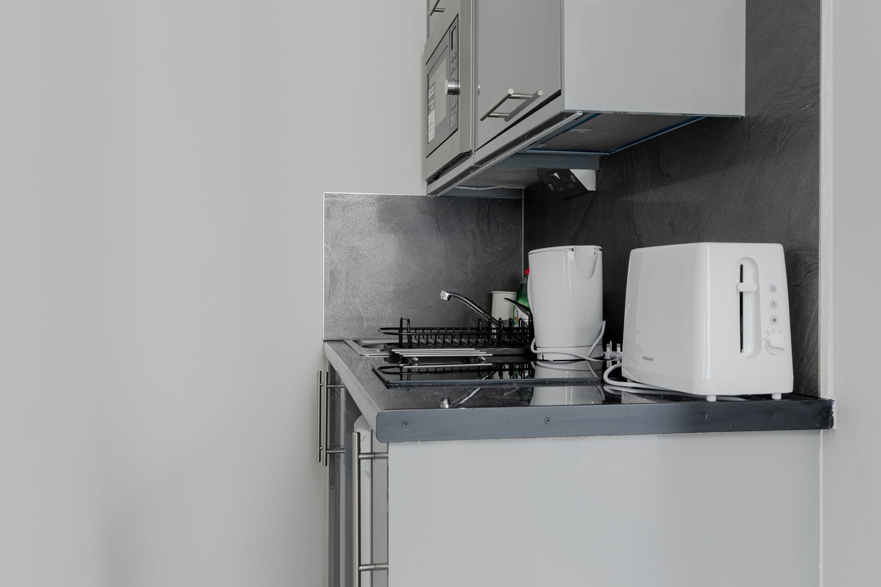 A kitchen with a stove, two white toasters, and a black backsplash.
