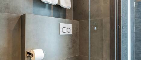 A modern bathroom with a glass-enclosed shower, a toilet, and a towel rack.
