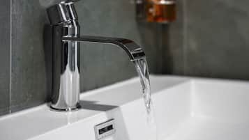 Een moderne badkamer met een chromen kraan en een zeepdispenser aan de muur.