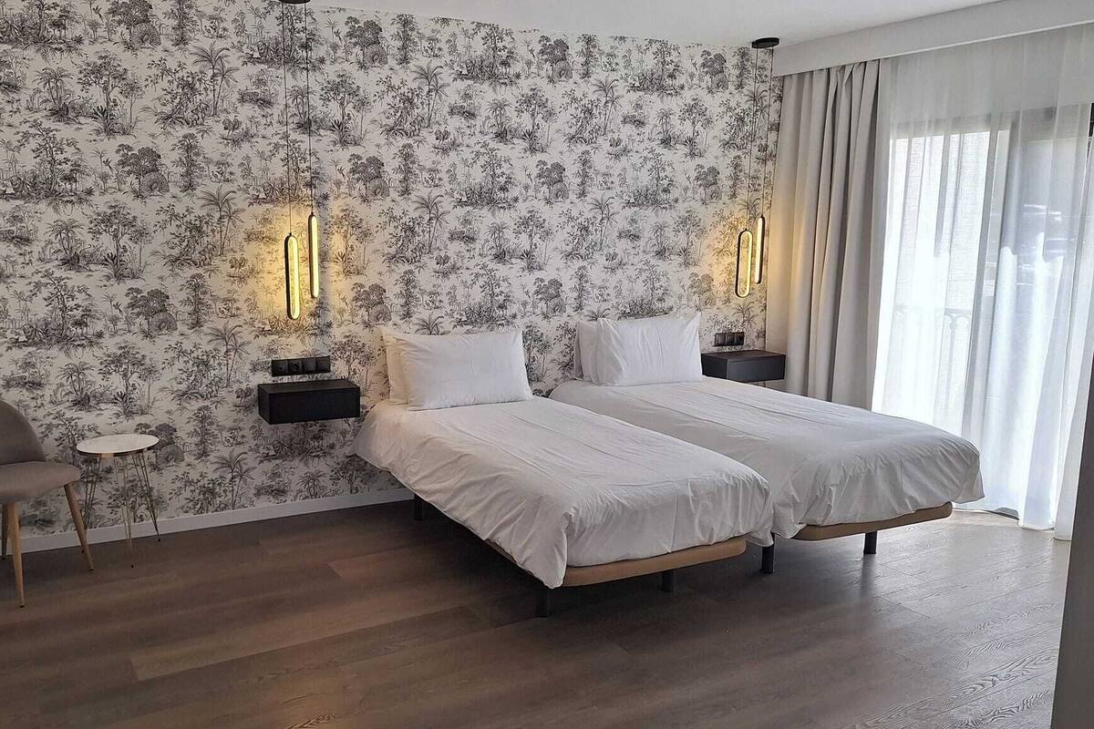 Une chambre d’hôtel avec un grand lit, deux tables de chevet, une chaise et une petite table.