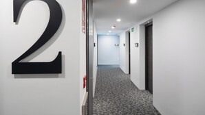Un pasillo con un gran número 2 negro, piso alfombrado y puertas que dan a habitaciones.