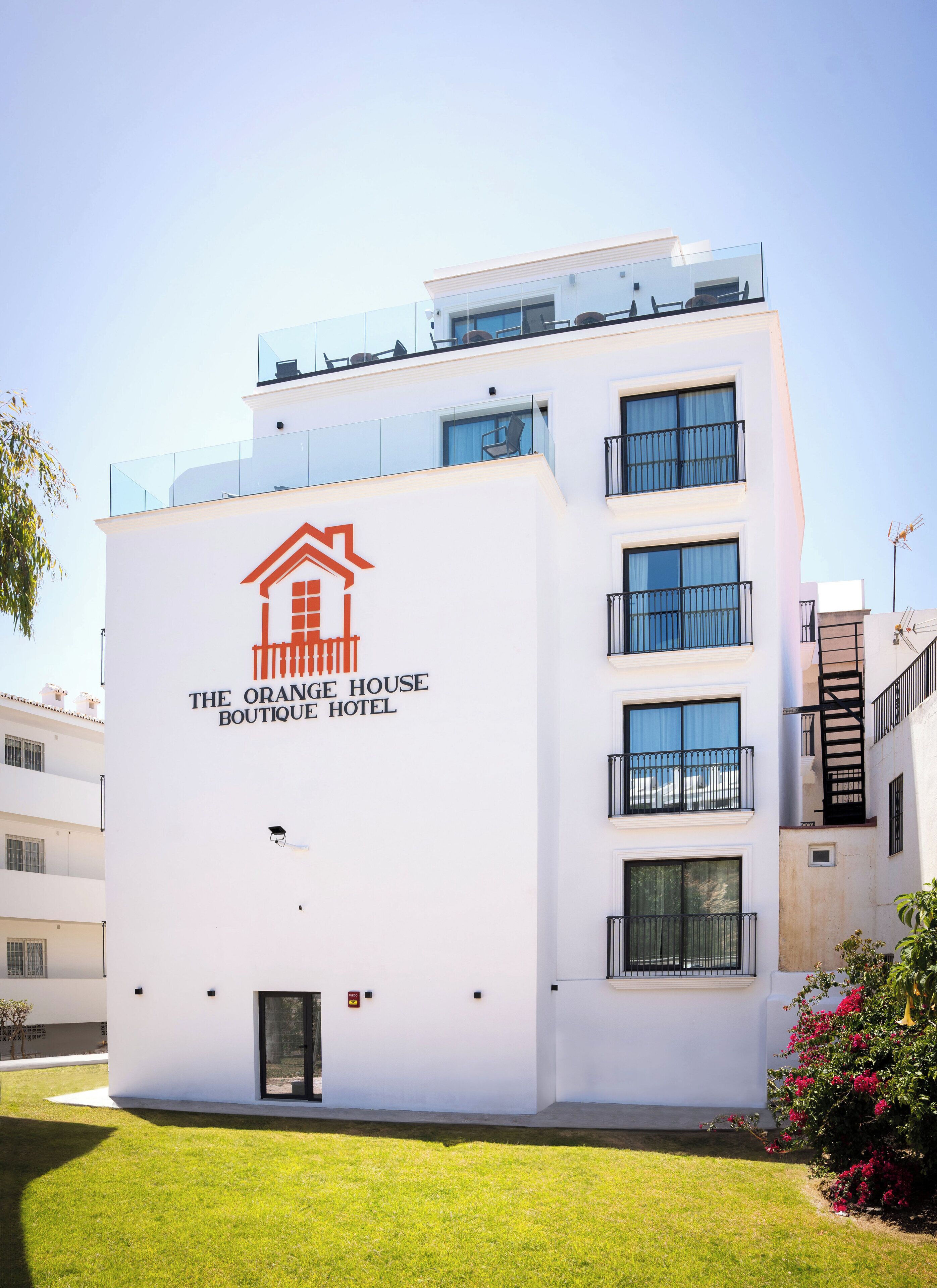 A modern hotel building with a prominent sign reading "The Orange House Boutique Hotel."