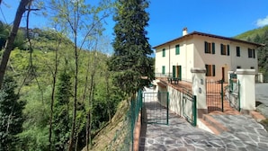 A two-story building with a stone-paved entrance and a green metal gate. - Lina romantic apartment Vallombrosa wifi nature (Toscana)