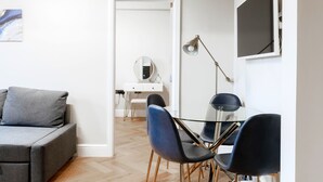 A modern room with a grey sofa, a desk with a mirror, and two blue chairs. - Bright One Bedroom Flats  (London)