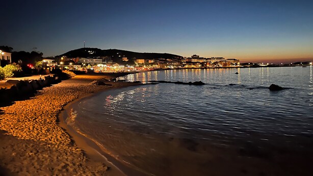 A coastal beach scene at dusk with a promenade and buildings along the shore. - Appartement Climatisé vue Imprenable sur Mer. 2 ch. Salon Cuisine SB Terrasse (L'Île-Rousse)