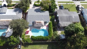 Una zona residencial con varias casas, una piscina y una construcción con techo de paja.