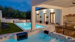 A modern outdoor pool area with hot tubs and a dining table. - NEW Apartment Villa Gironi with Pool and Jacuzzi (Tugare)