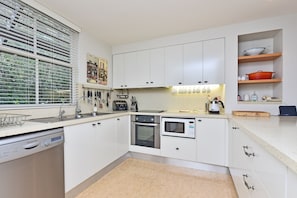 A modern kitchen with white cabinetry, a built-in oven, a microwave, and a dishwasher.