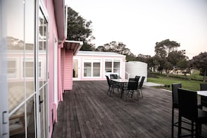 A pink building with a deck and outdoor seating area.