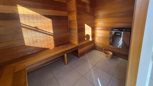 A wooden cabin interior with a bench, a sauna, and a small wooden bucket. - Heart of Lovedale (Keinbah)