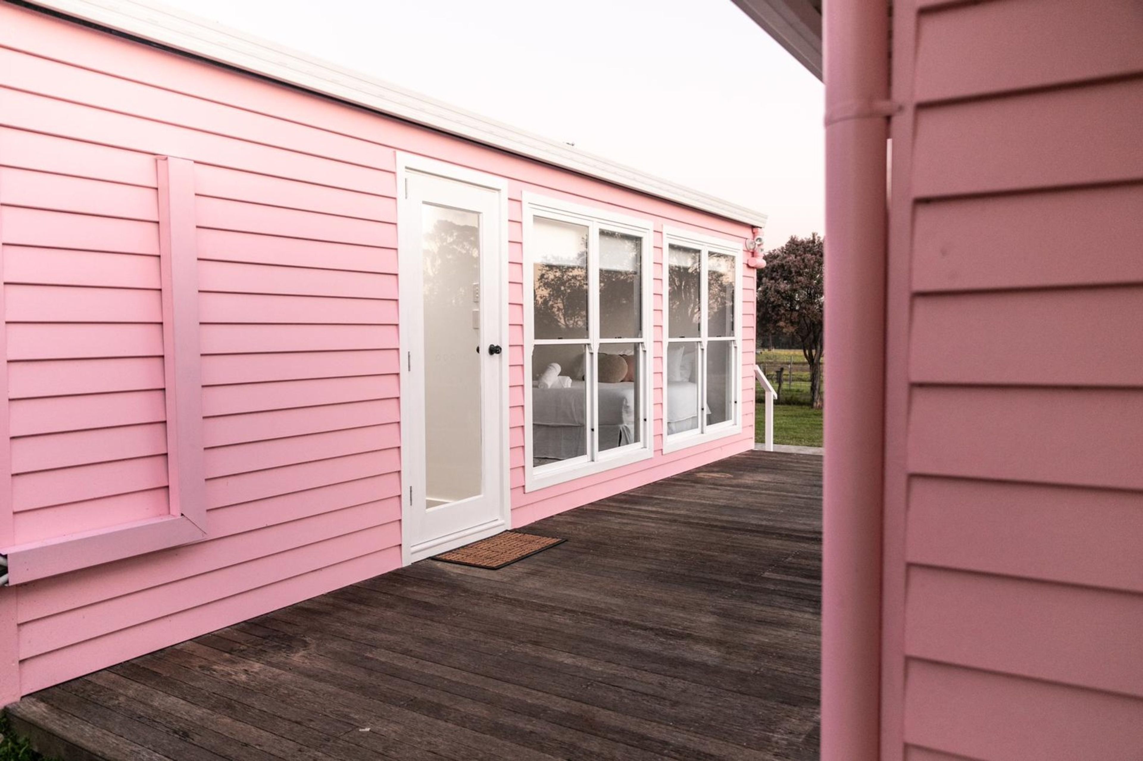 A pink house with a covered porch and a white door.