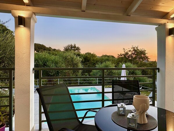 Ein Balkon mit Pool, Tisch und Stühlen sowie Blick auf die umliegende Grünfläche.