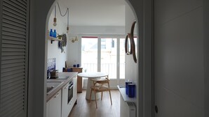 Una cocina con armarios blancos, una mesa redonda y una silla de madera.