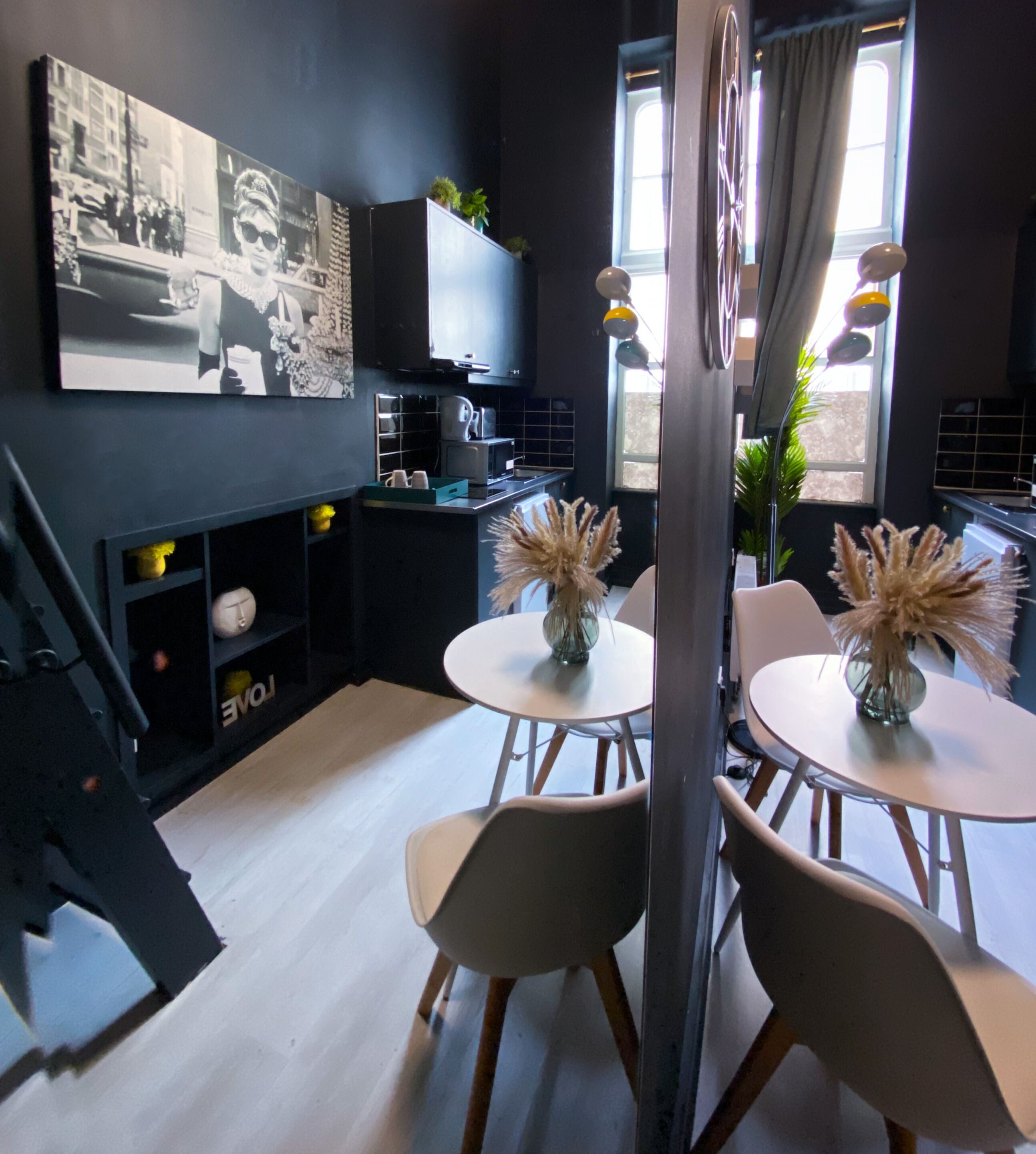Une cuisine moderne équipée d’un téléviseur à écran plat, d’un coin repas avec deux chaises et une table, et d’un escalier menant à un autre niveau.