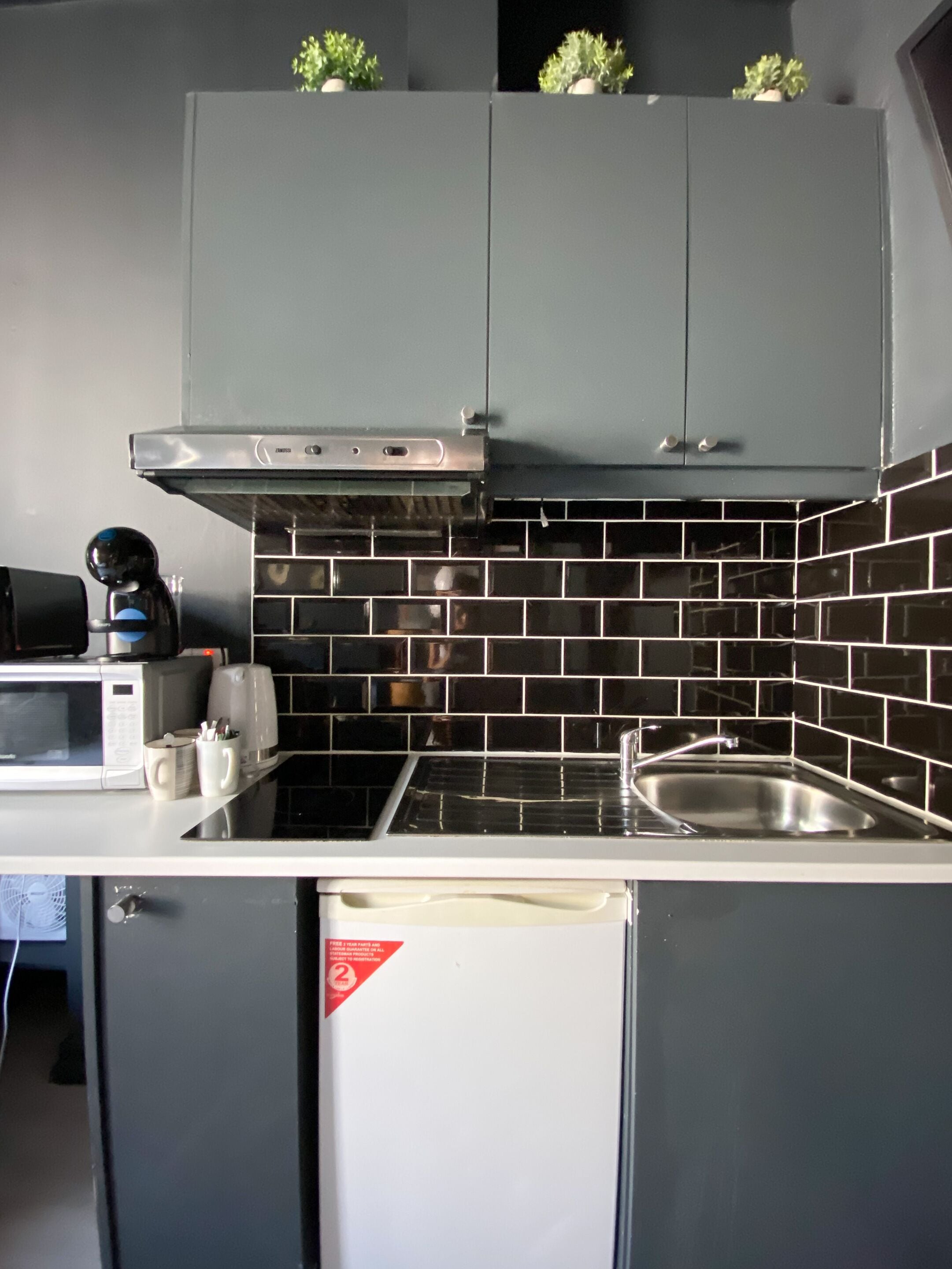 A compact kitchen with a microwave, coffee maker, and a small refrigerator.