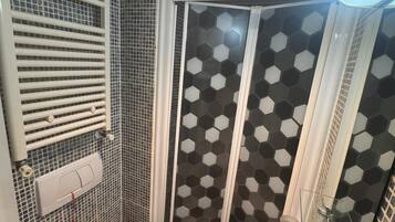 A bathroom with a toilet, bidet, and shower with a hexagonal tile pattern.