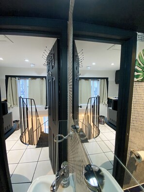 Un baño moderno con mampara de vidrio, lavamanos y zona de ducha.