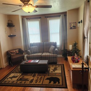 A living room with a plaid sofa, ottoman, and a rug with animal prints.
