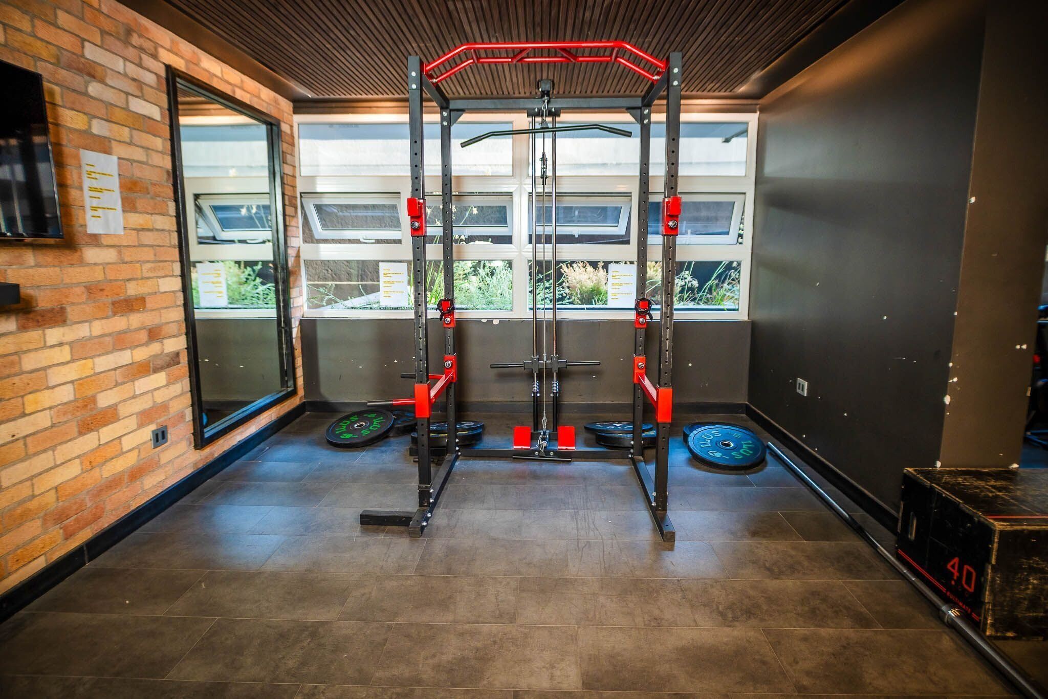 A gym with a squat rack, weight plates, and a digital timer.