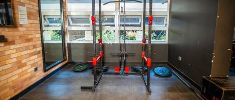 A gym with a squat rack, weight plates, and a digital timer.
