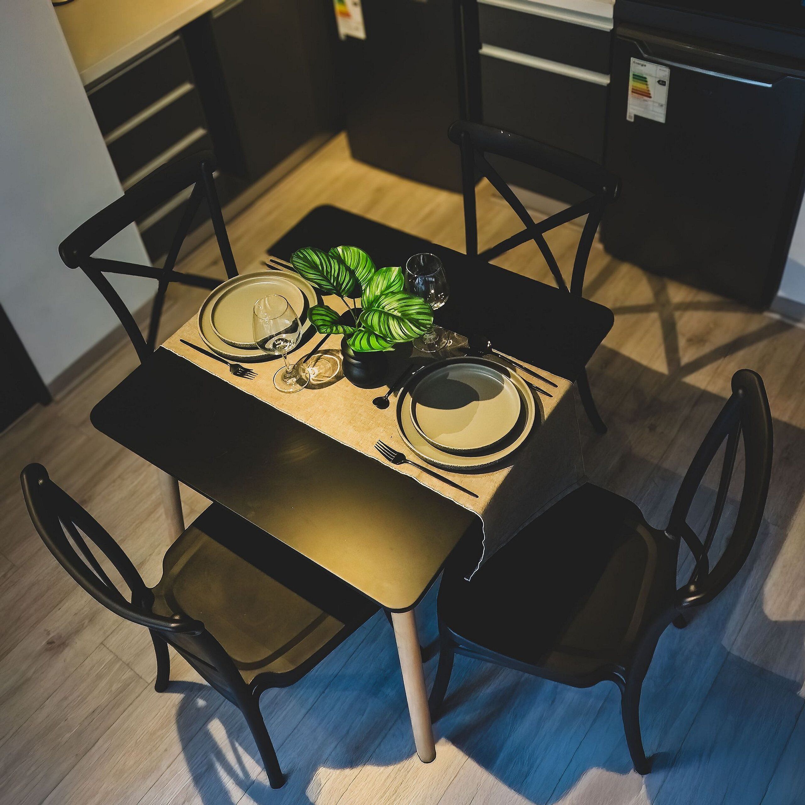A dining table set with plates, cutlery, and a potted plant.