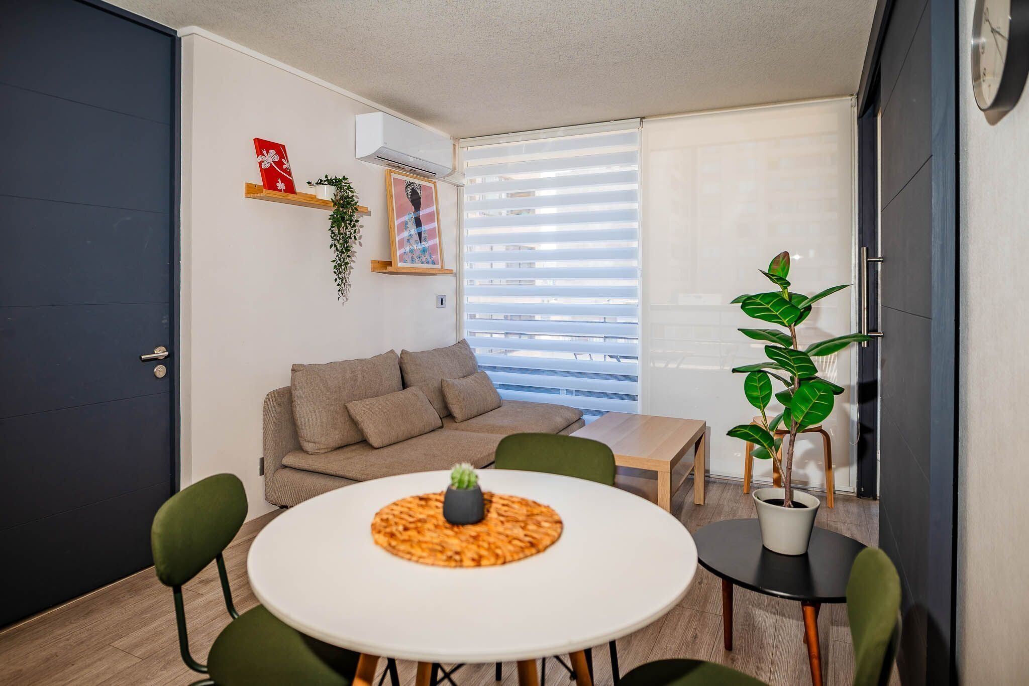 A compact living space with a round dining table, a sofa, and a potted plant.