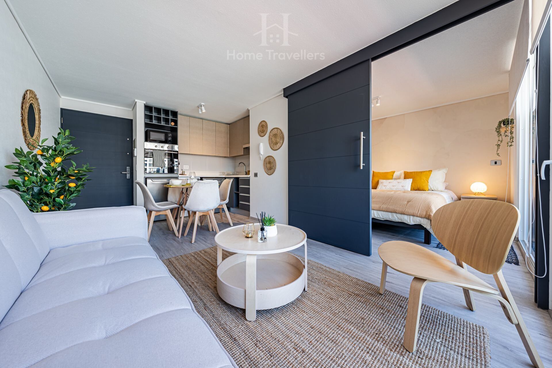 Een moderne, compacte woonruimte met een bank, een eethoek en een bed.