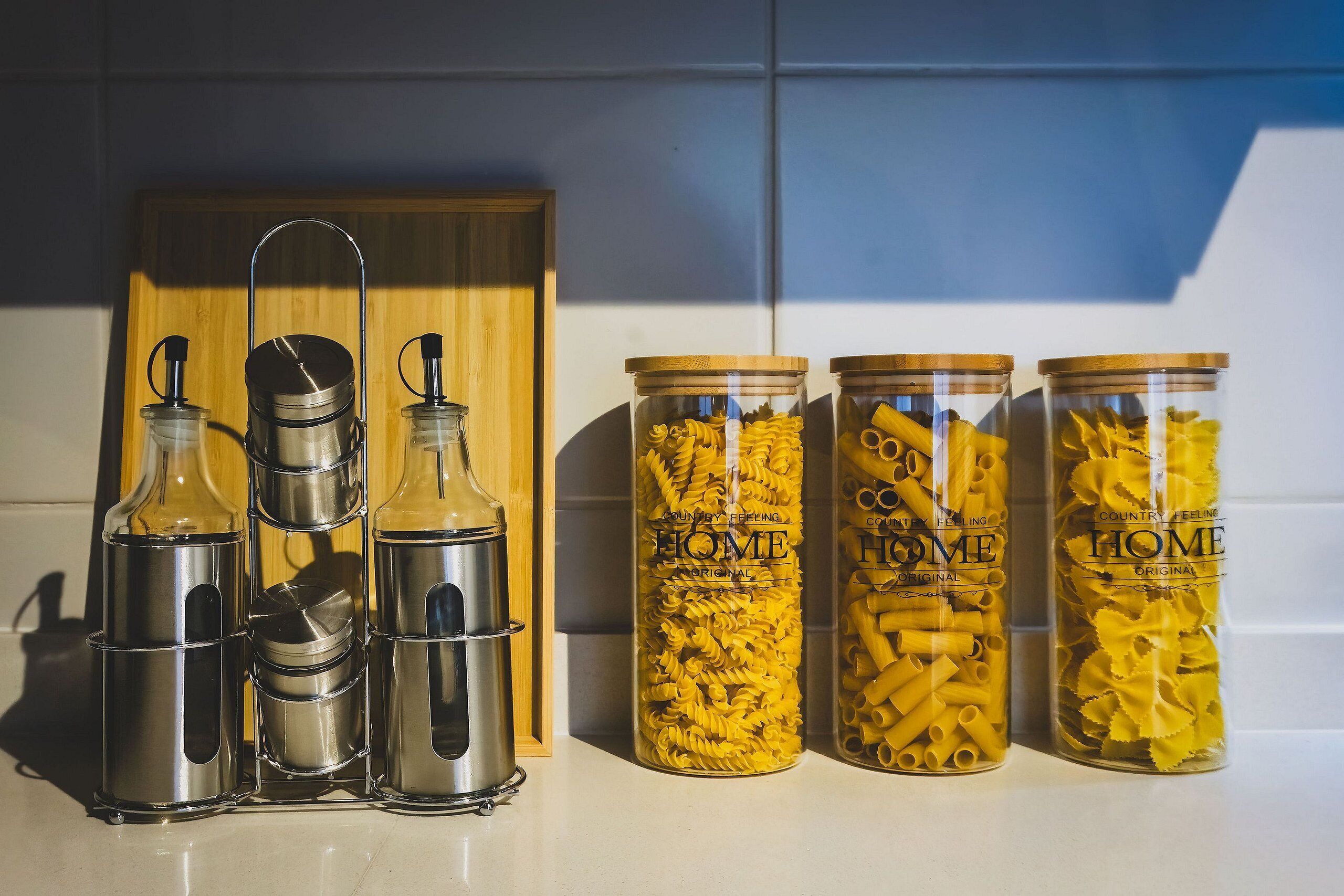 Four stainless steel water bottles and three glass jars with pasta.