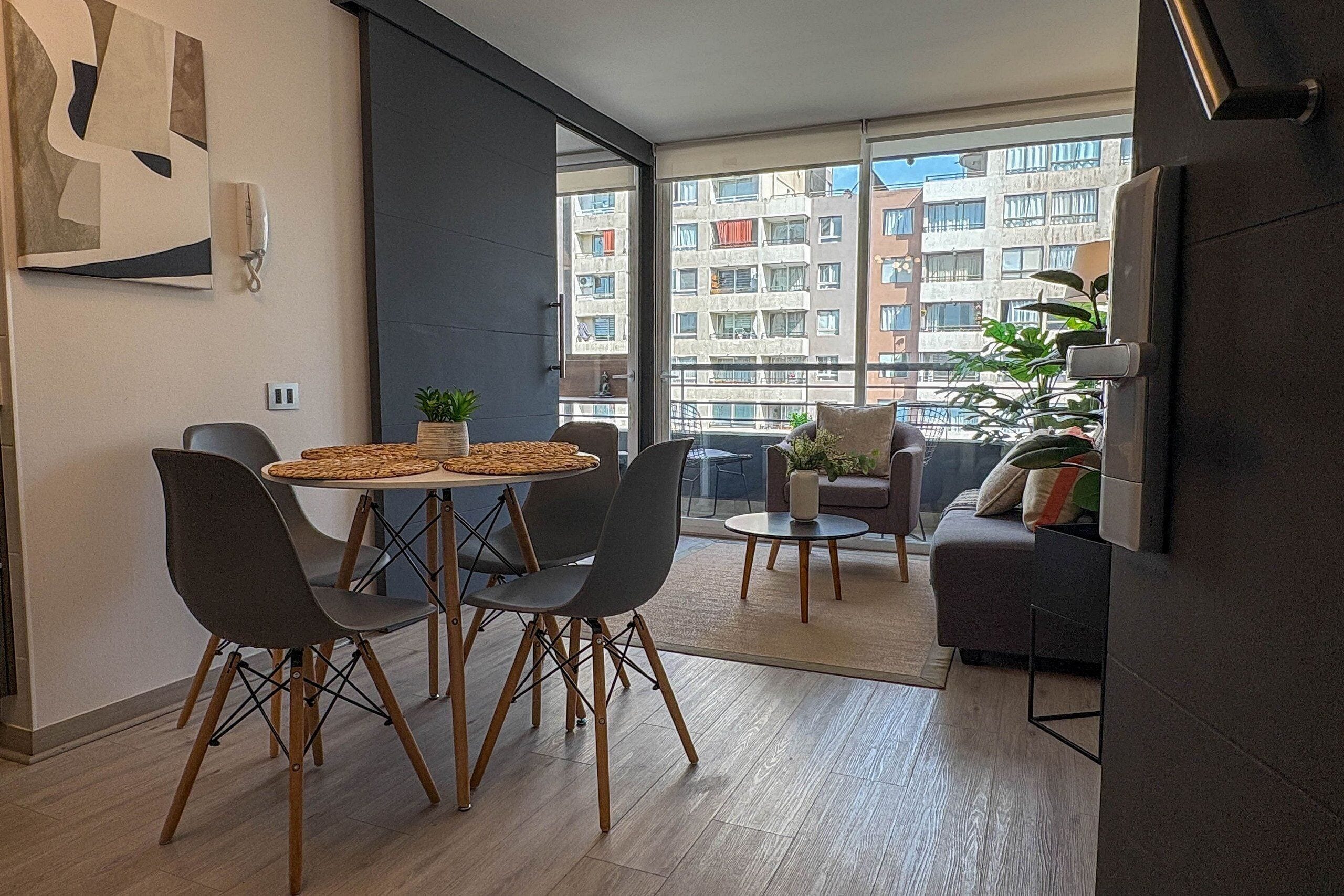 A modern apartment with a dining area, a sofa, and a balcony with a view of the city.