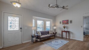 A living room with a sofa, a coffee table, a rug, a door with a stained glass window, and a ceiling fan. - Disney Castle Cove - Private Pool & Community Boat Ramp close to Legoland (Winter Haven)
