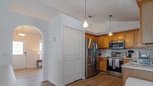 A modern kitchen with stainless steel appliances, wooden cabinets, and a white countertop. - Disney Castle Cove - Private Pool & Community Boat Ramp close to Legoland (Winter Haven)