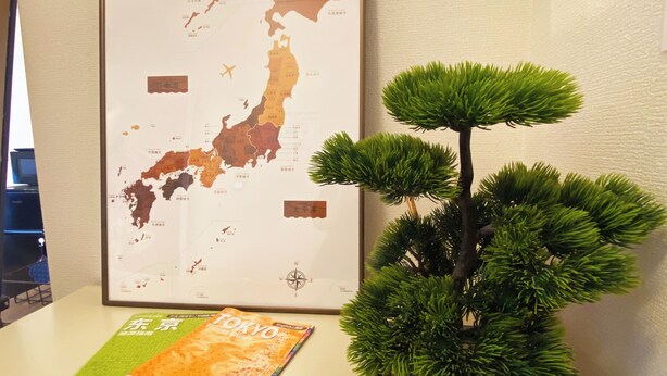 A framed map of Japan, a bonsai tree, and a travel guidebook on a table. - 1minute walk to station, direct bus to Haneda Airport! Easy access! (大田区)