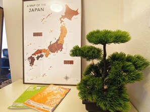 A framed map of Japan, a bonsai tree, and a travel guidebook on a table.