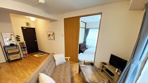 A compact living space with a sofa, a small wooden table, a television, and a mirror. - 1minute walk to station, direct bus to Haneda Airport! Easy access! (大田区)
