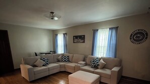 A living room with a L-shaped sectional sofa, a small coffee table, and a ceiling fan. - Walk Anywhere PSU! 3BR home in College Heights.  Summer discount now! (State College)