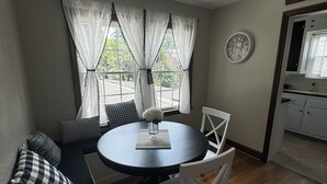 A dining area with a round table, white chairs, and a black sofa with checkered pillows. - Walk Anywhere PSU! 3BR home in College Heights.  Summer discount now! (State College)