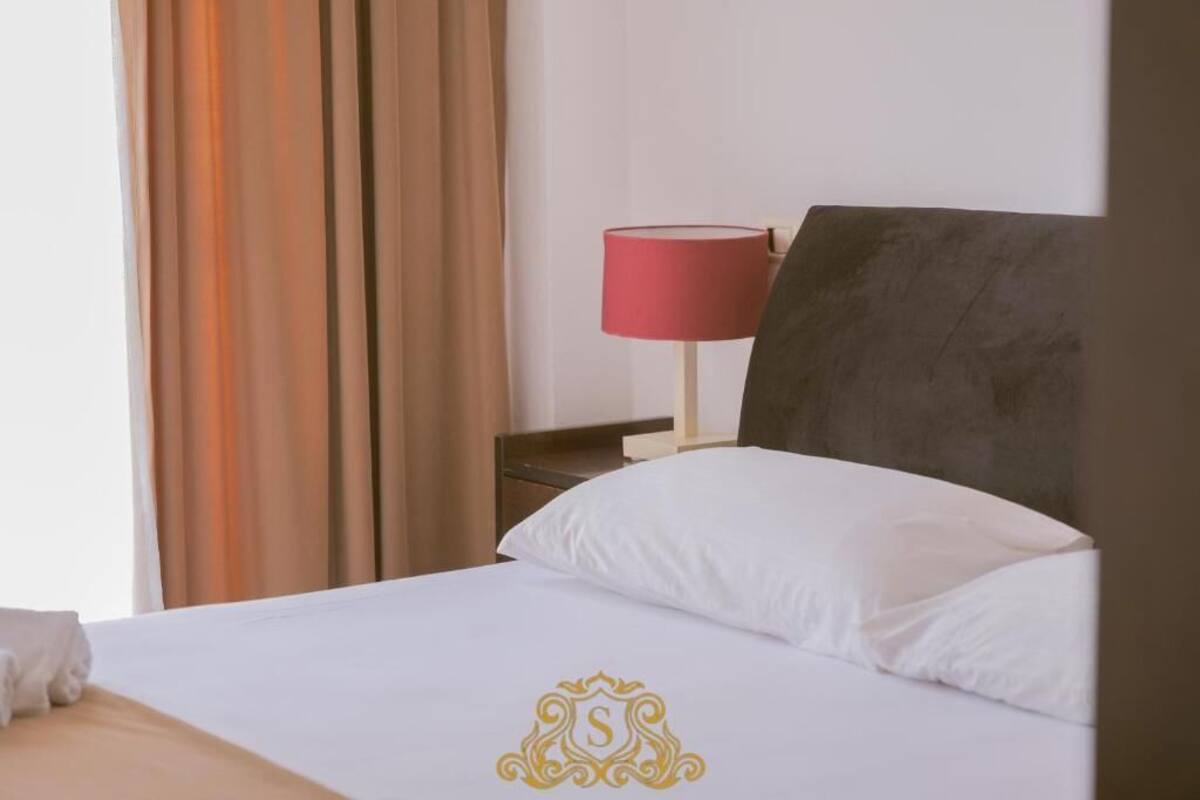 A hotel room with a bed, a red lamp, and curtains.