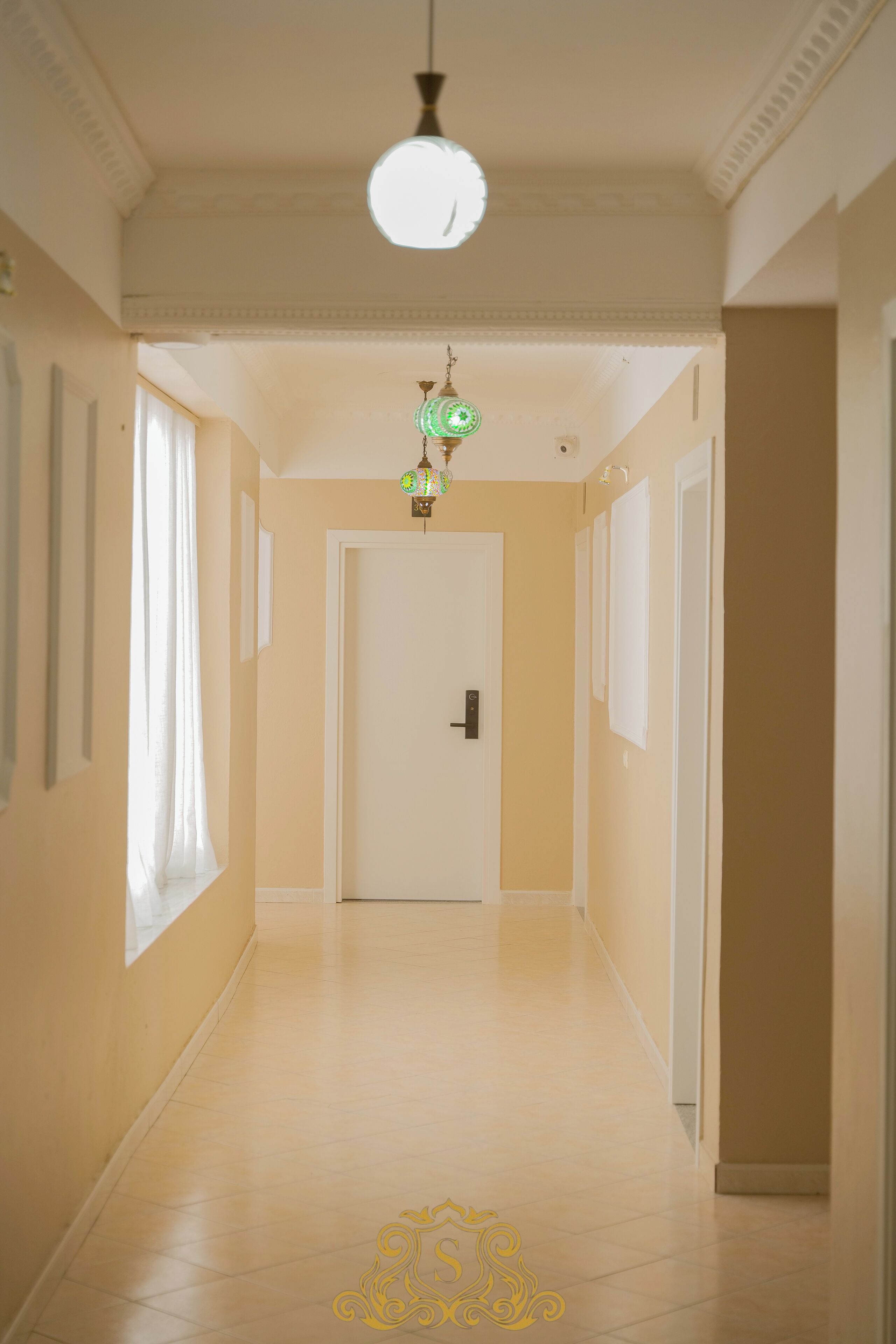 A hallway with a door at the end, light-colored walls, and a patterned floor.