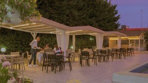Uma área de refeições ao ar livre com assentos cobertos e uma piscina.