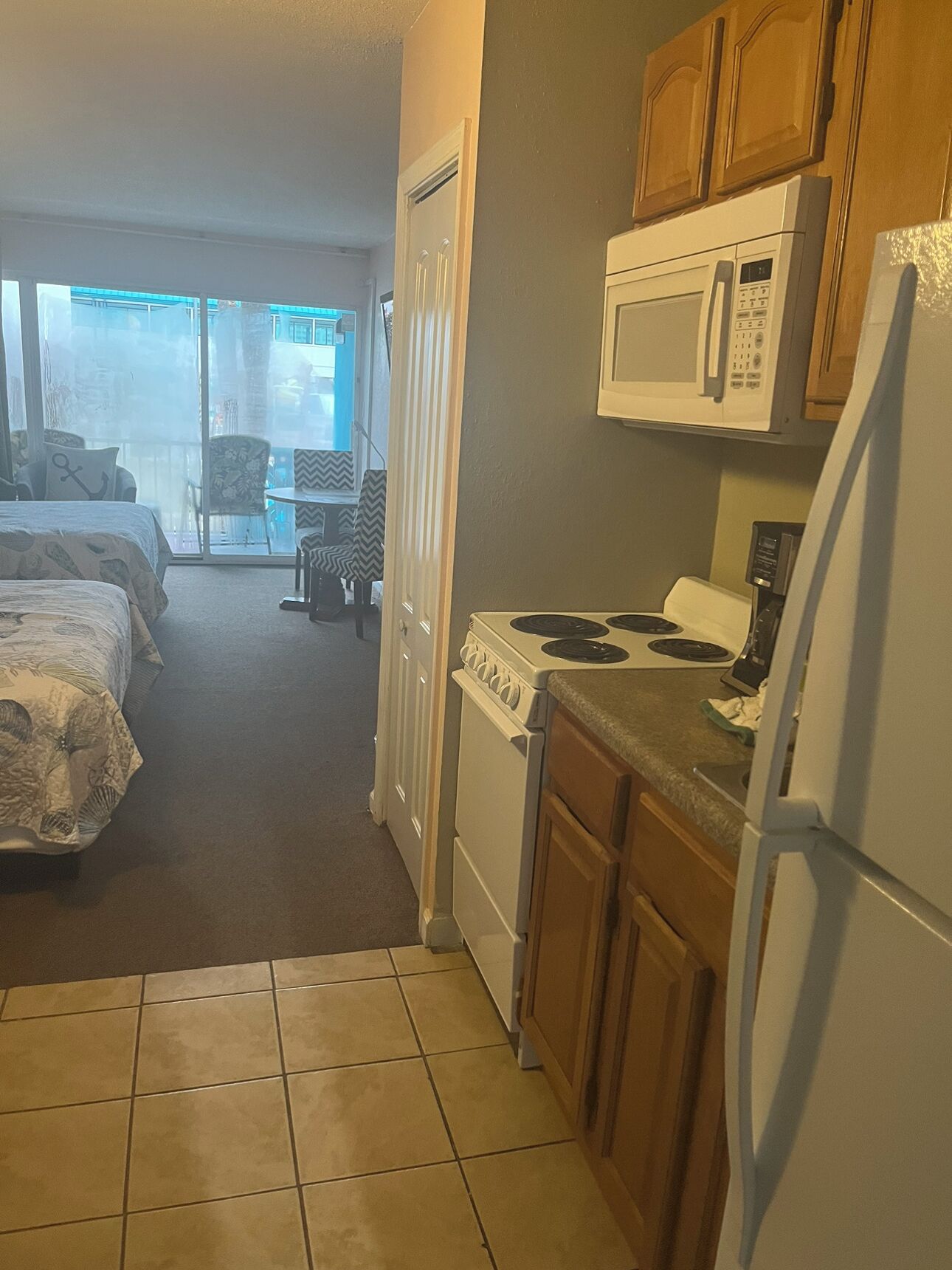A compact kitchen with a stove, microwave, and refrigerator.