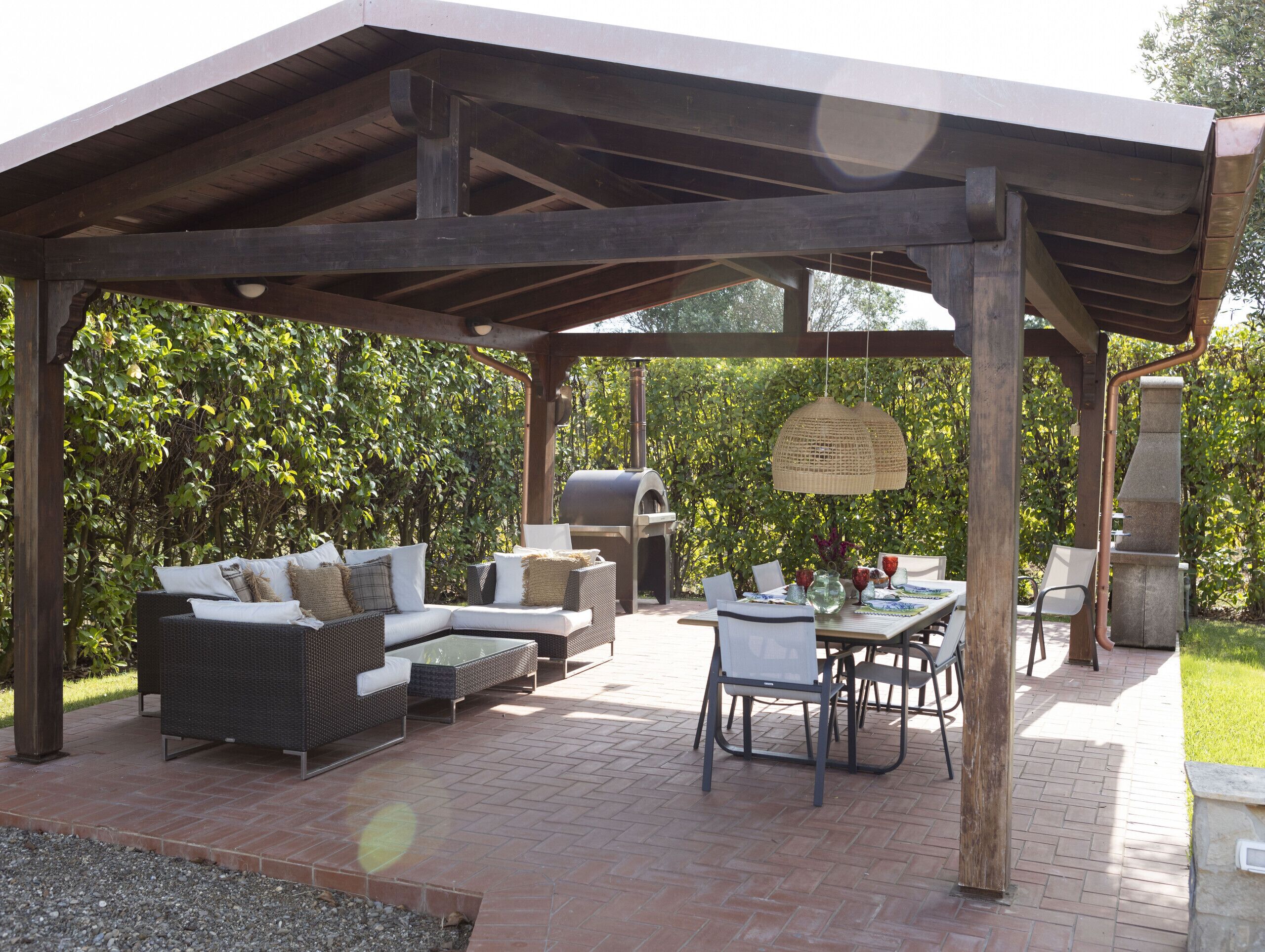 An outdoor patio with a covered seating area, a grill, and a dining table with chairs.