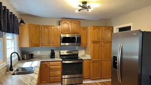 A kitchen with wooden cabinets, stainless steel appliances, a marble countertop, and a built-in oven. - Mountain Mama (Hendersonville)