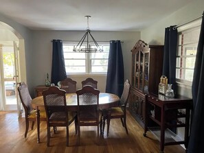 Una sala da pranzo con un tavolo rotondo, sei sedie, un lampadario e una credenza con ante in vetro.