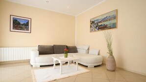 A living room with a white sofa, a white coffee table, a vase with flowers, and two paintings on the walls. - Apartment  with a sea view (Baska)