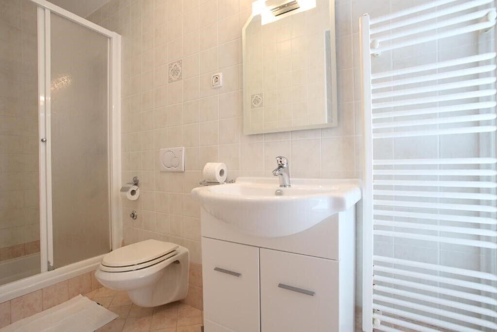 A bathroom with a shower, toilet, sink, and mirror.