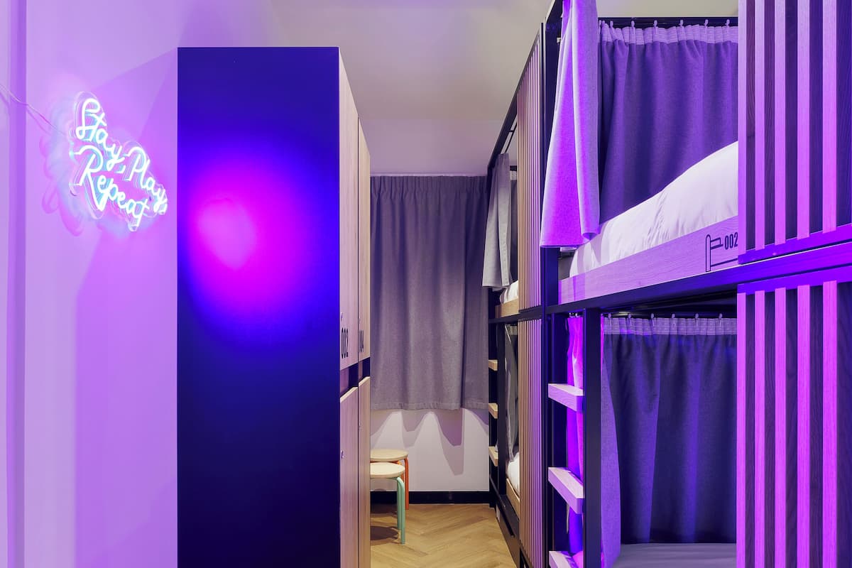 A room with bunk beds, a neon sign, and a wooden floor.