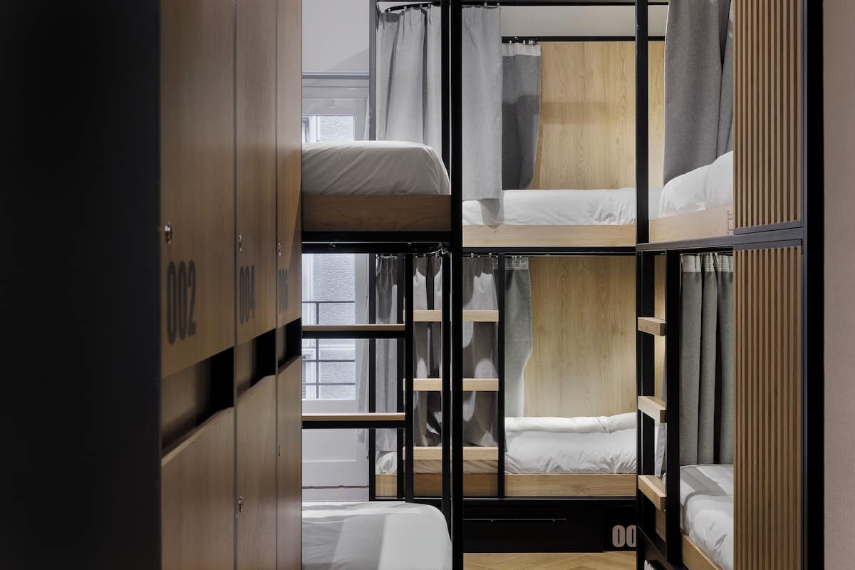 A bunk bed room with wooden headboards, a window, and a wardrobe.