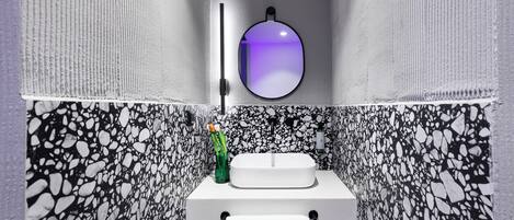 A bathroom with a white sink, a towel hanging on a rack, and a mirror with a purple reflection.